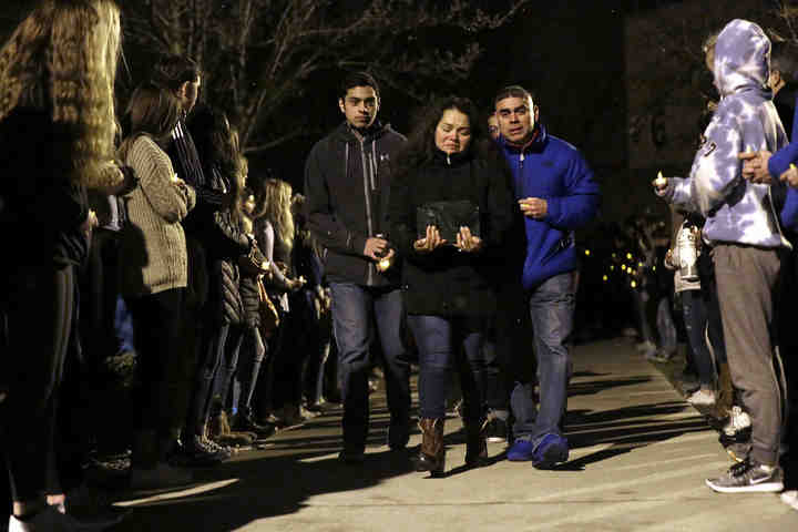 Evelia Morales holds on tightly to the remains of her son, Andrew Morales, as she and her husband, Fernando Morales (right) and son, Luis Morales, make their way past rows of Dublin Coffman students and faculty after a vigil held in Andrew's honor at Dublin Coffman High School. Andrew died unexpectedly during a symphonic band practice March 5.    (Shane Flanigan / ThisWeek Community News)